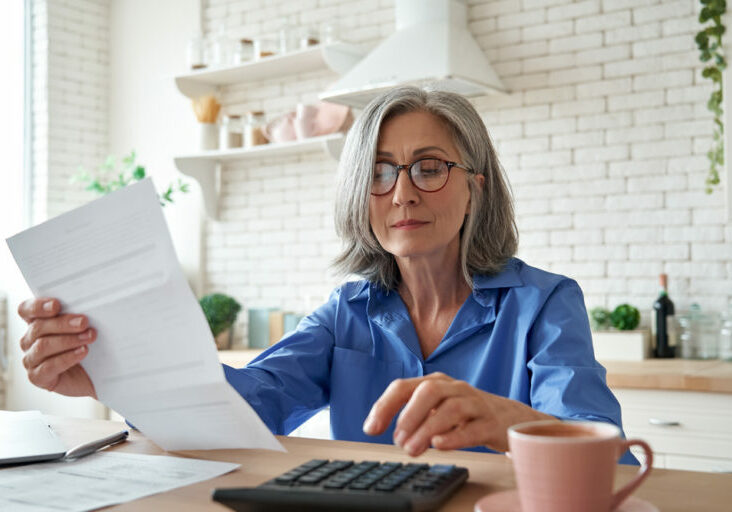Senior,Mature,Business,Woman,Holding,Paper,Bill,Using,Calculator,,Old